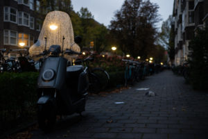 Skuter i rowery zaparkowane pod kamienicami, Amsterdam
